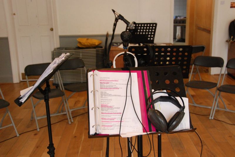 A music stand with a manuscript and set of headphones.