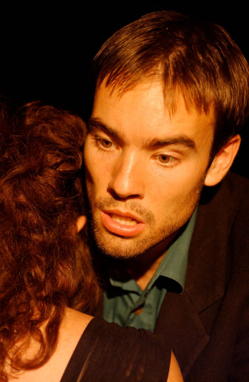 Krogstad in a close up confronting Nora (whose face is not seen). His facial expression is sugesting desparation.