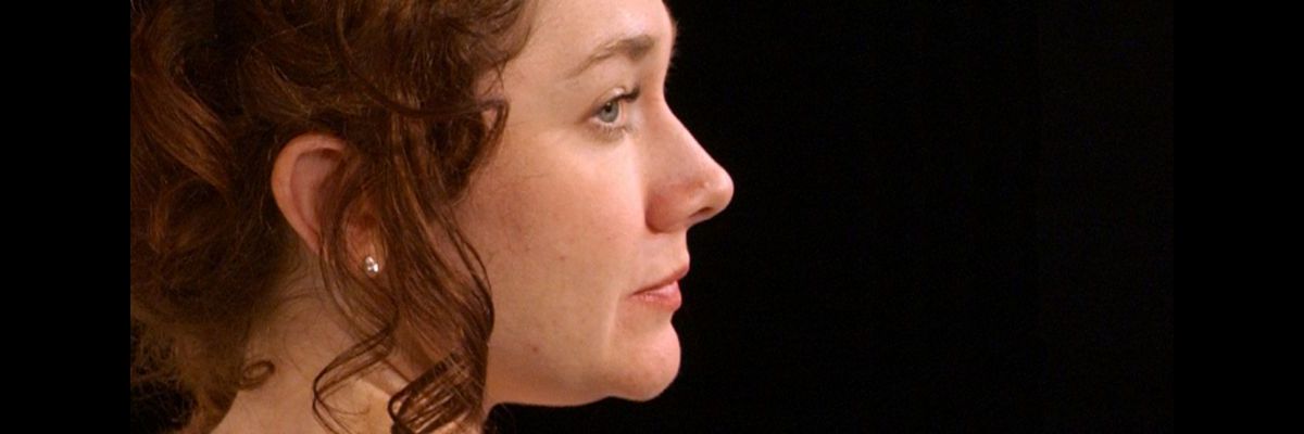 Close up in profile of Sarah Head as Nora.