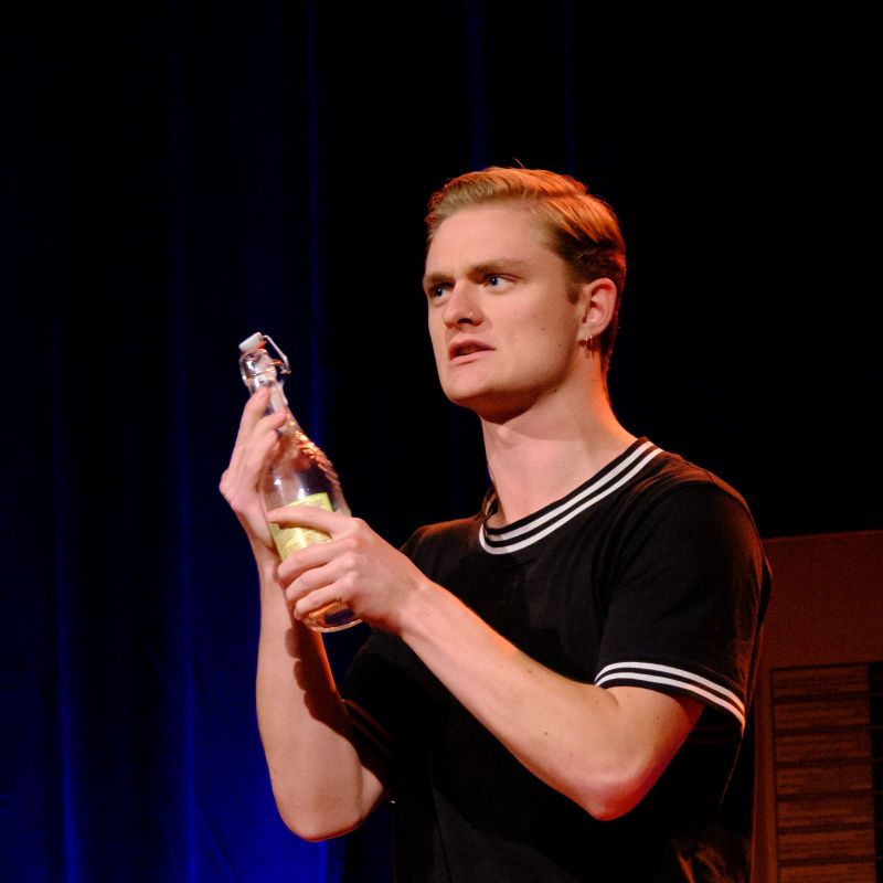 A young man is holding a a bottle.