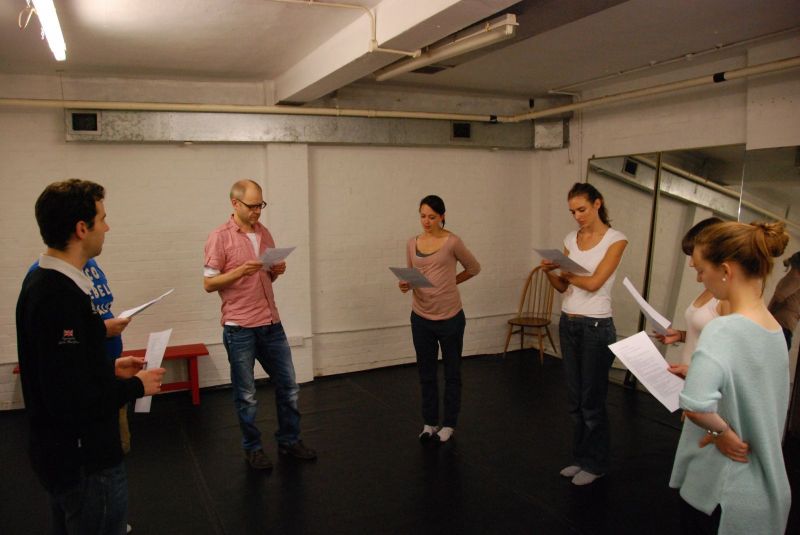 Actors study a piece of text in a workshop.