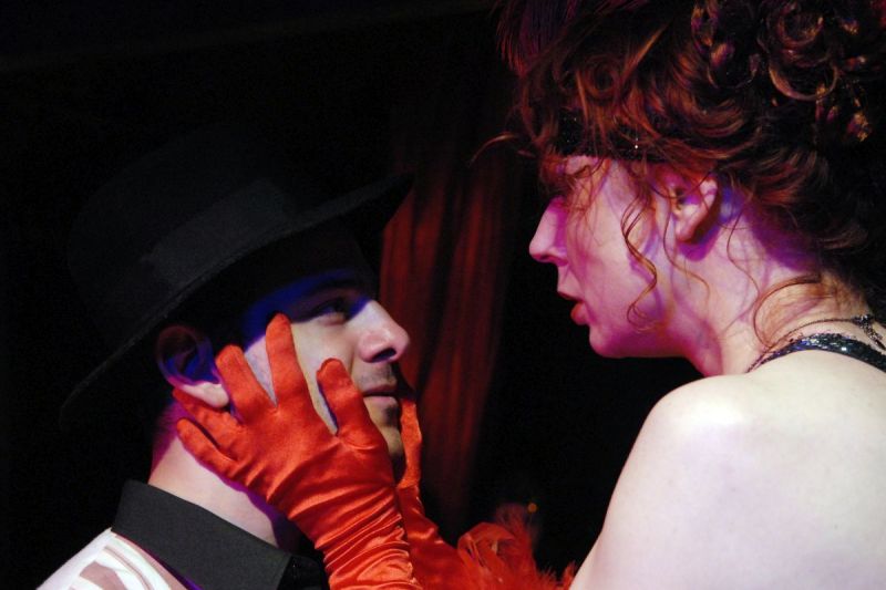 Miss Kabaret Button-Moulder is holding Peer Gynt&#039;s face tight with both hands. She is wearing red long-sleeve satin gloves.