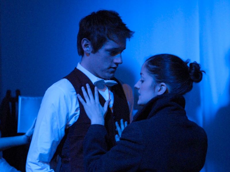 A reunion between young couple whose body language is suggesting a desire for each other. The stage is lit in blue.
