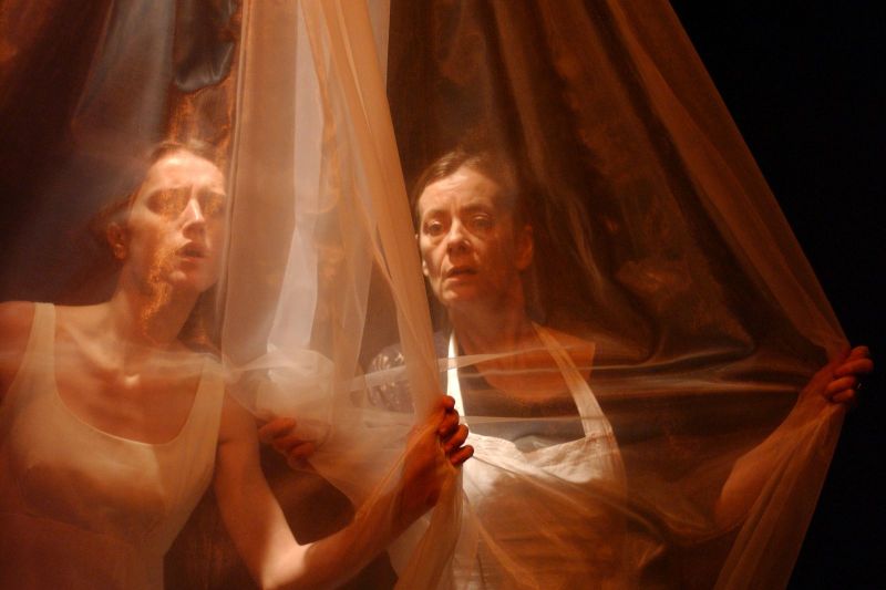 The housekeeper, Madam Helseth, and Beate Rosmer are hiding behind a white gauze suggesting they are looking through a net curtain.